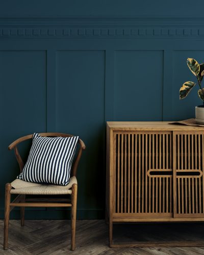 Scandinavian vintage wood cabinet with chair by a dark blue wall